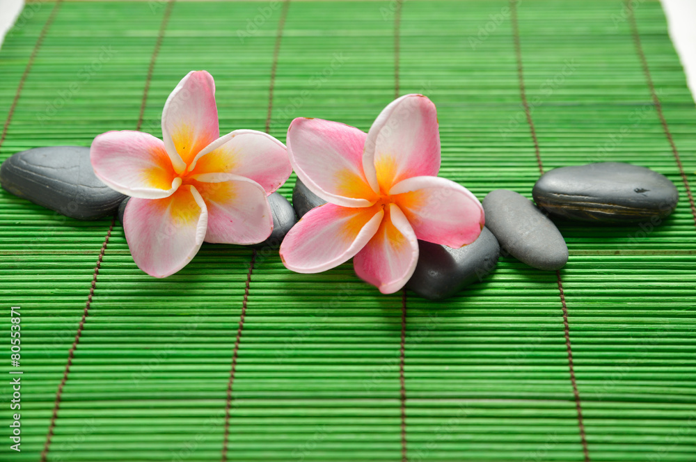 Set of stones with two frangipani on green mat Set of stones with two frangipani on green mat