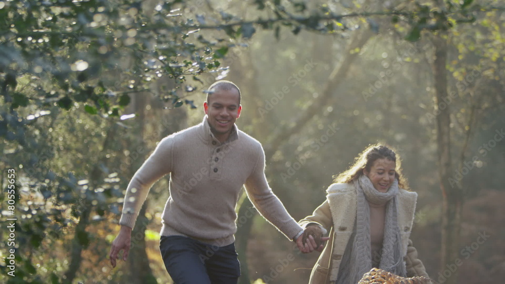 Attractive couple running through the forest and exercising their dog Attractive couple running through the forest and exercising their dog