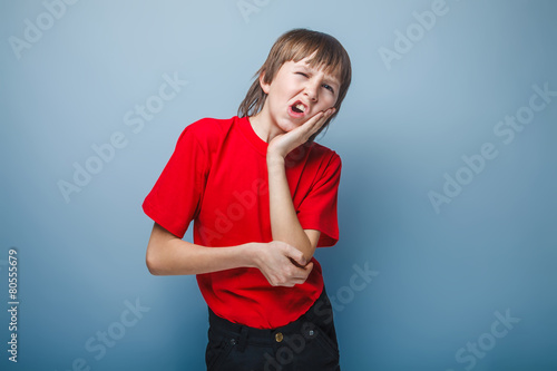 boy teenager European appearance holds a hand on his cheek wrink photo