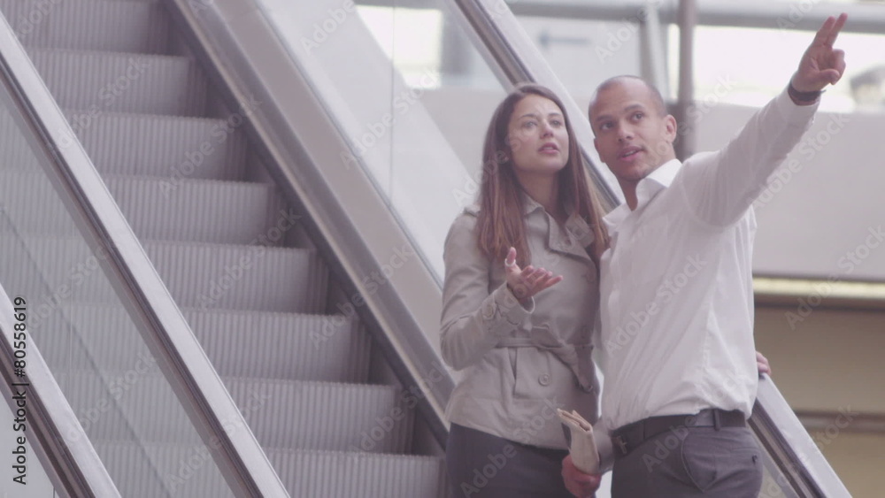 Attractive young couple chat as they ride the escalator Attractive young couple chat as they ride the escalator