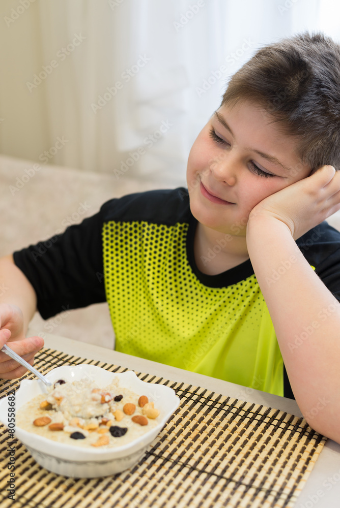 Teenager boy has oatmeal for breakfast Teenager boy has oatmeal for breakfast
