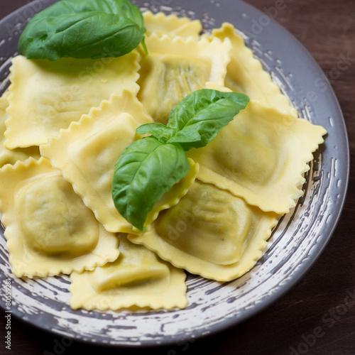 Close-up of italian square ravioli with fresh green basil leaves