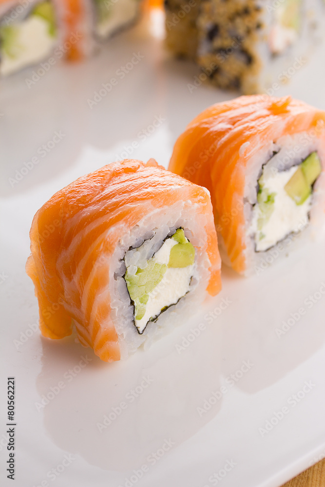 Sushi set on white plate over wooden background Sushi set on white plate over wooden background