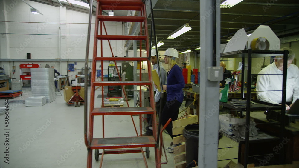Staff members in a busy warehouse, each carrying out their own roles Staff members in a busy warehouse, each carrying out their own roles