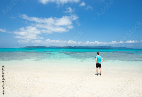 Man overlooking view of tropical white sand beach paradise lagoon full of healthy coral reef in Okinawa