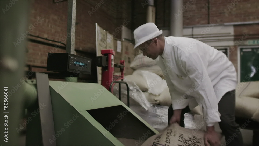 Workers in a factory or warehouse handling large sacks of fresh coffee beans Workers in a factory or warehouse handling large sacks of fresh coffee beans
