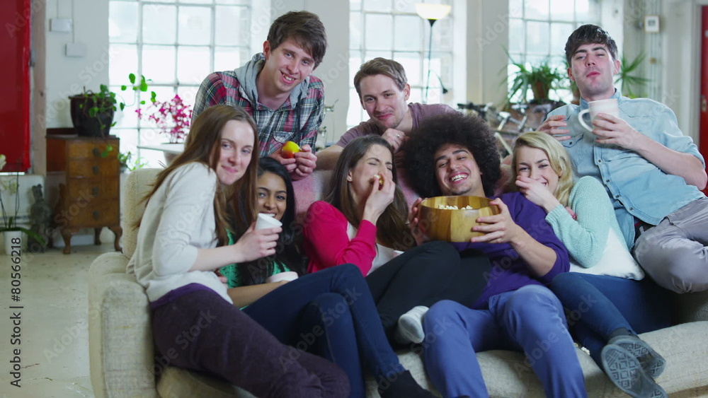 Happy group of friends relaxing on the sofa, eating popcorn and watching TV Happy group of friends relaxing on the sofa, eating popcorn and watching TV