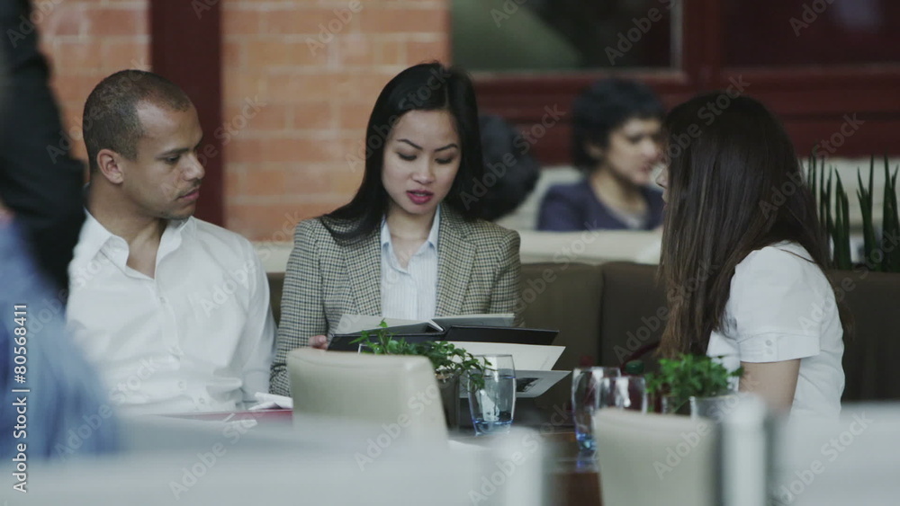 Group of friends at a restaurant looking at the menu and deciding what to order Group of friends at a restaurant looking at the menu and deciding what to order