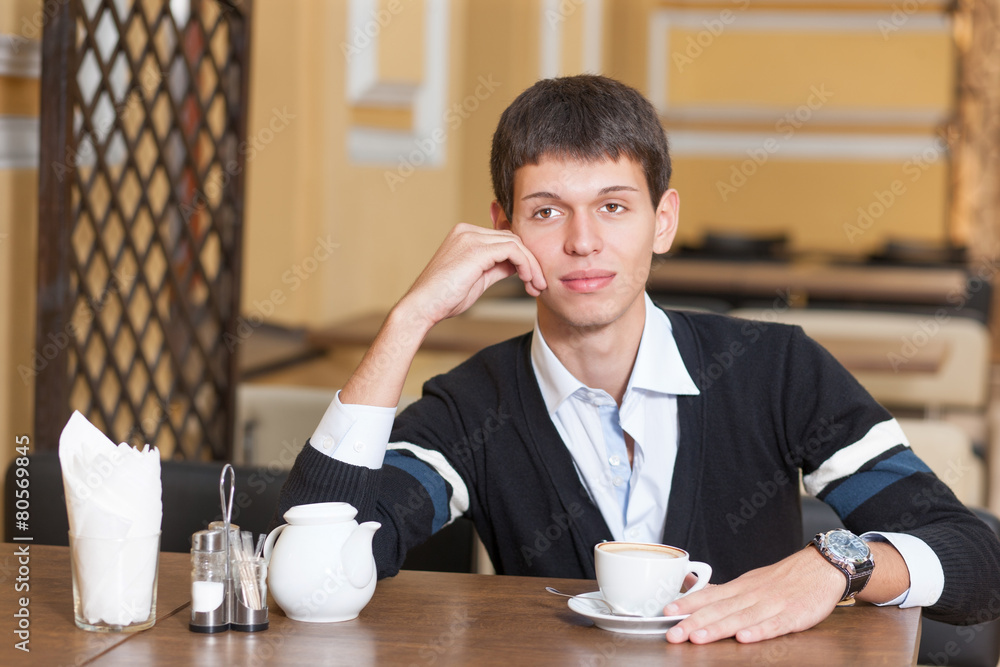 Young man across table with cup of coffee Young man across table with cup of coffee