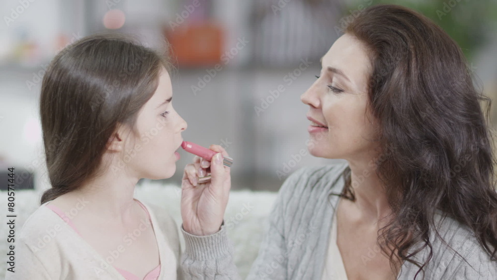 Attractive woman teaches her daughter how to put on lipstick Attractive woman teaches her daughter how to put on lipstick