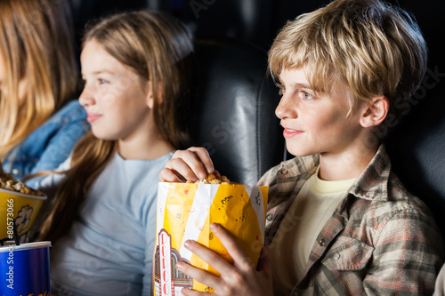 Boy Eating Popcorn While Watching Movie With Family