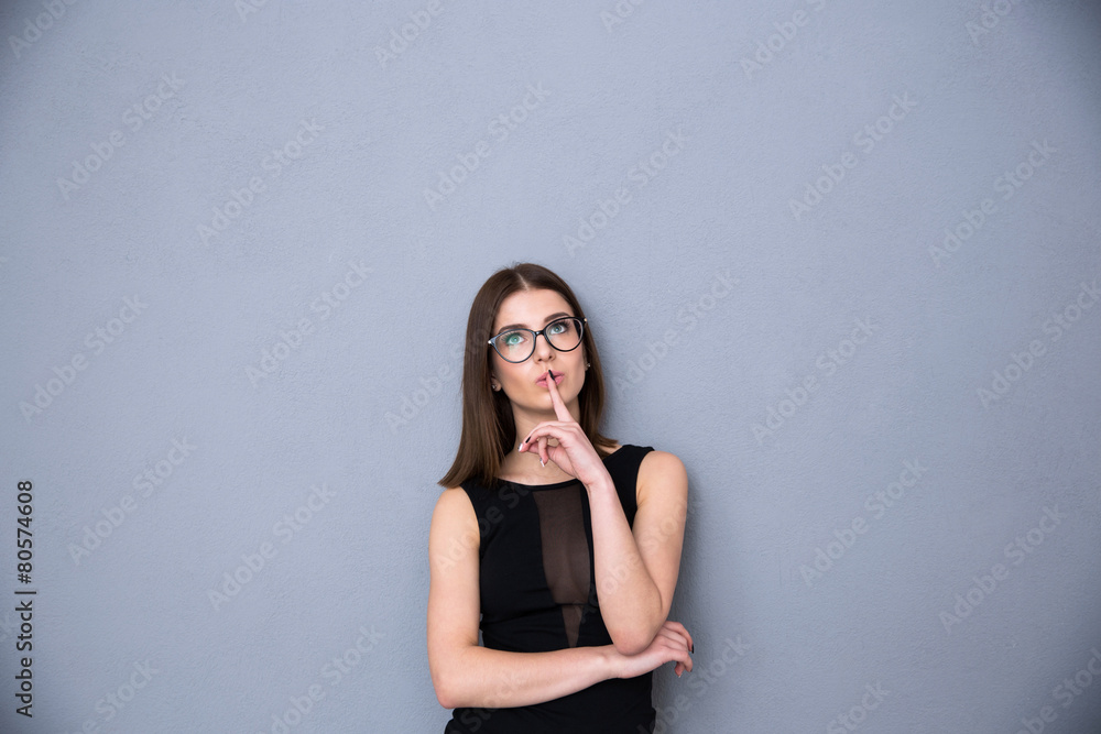 Attractive woman with finger over lips looking up at copyspace Attractive woman with finger over lips looking up at copyspace