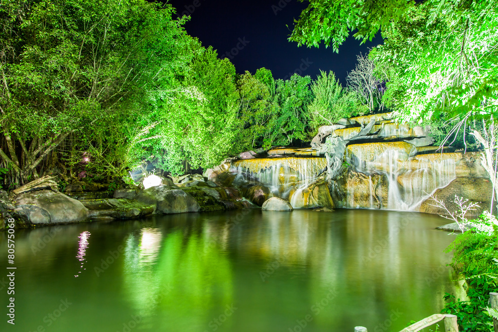 Waterfall with light from lamp in night garden Waterfall with light from lamp in night garden