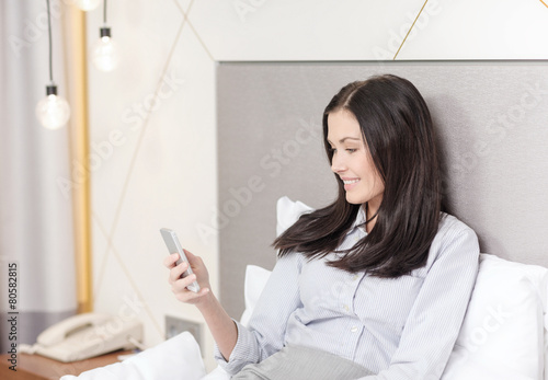 happy businesswoman with smartphone in hotel room