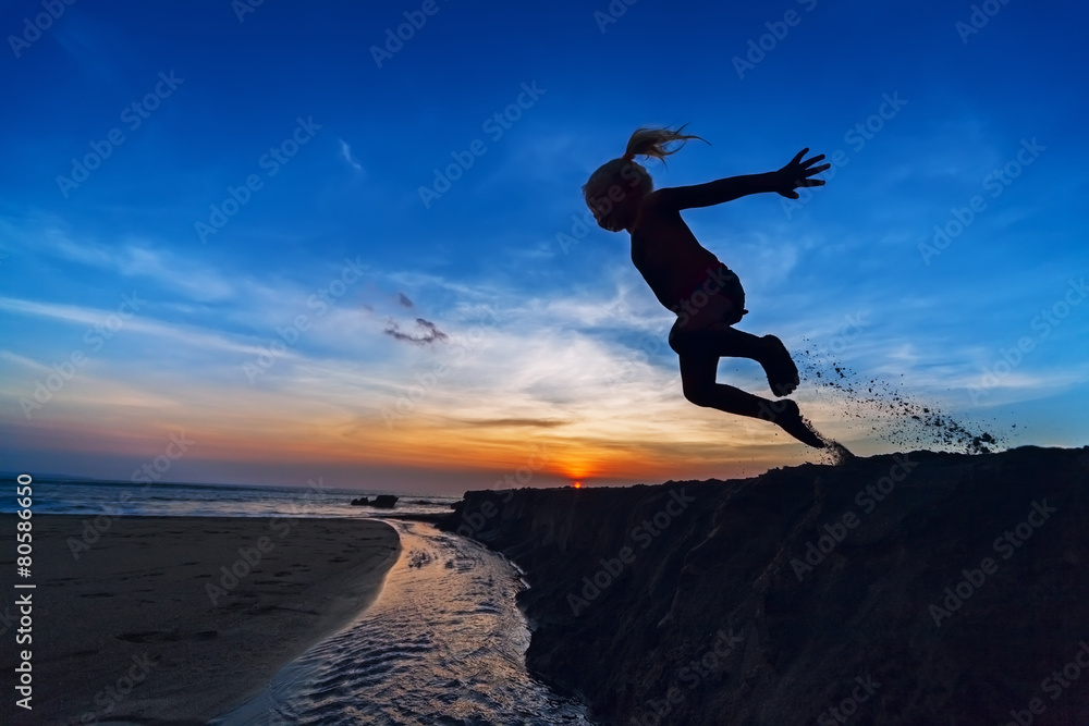 Girl jumping on the sunset beach
