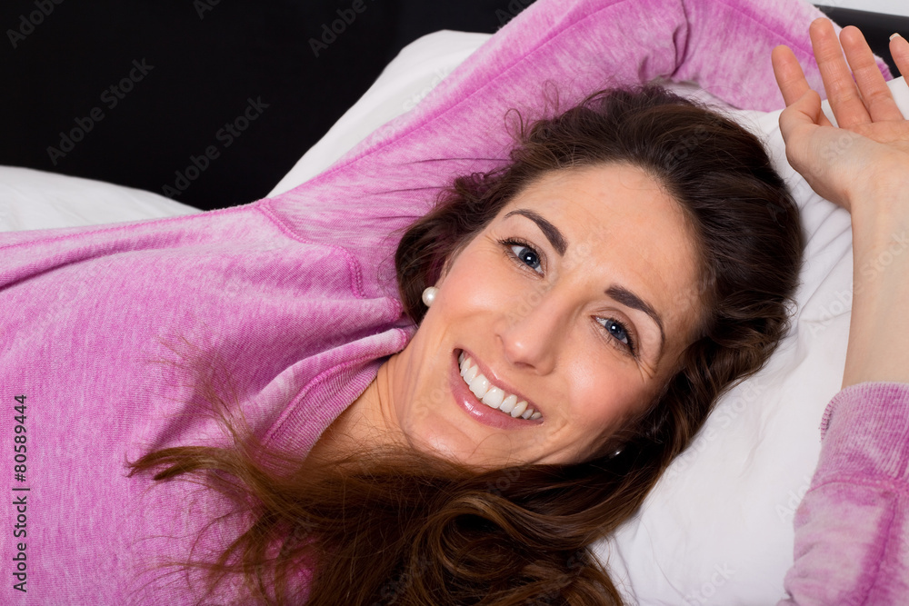 Fototapeta premium happy young woman lying on her bed