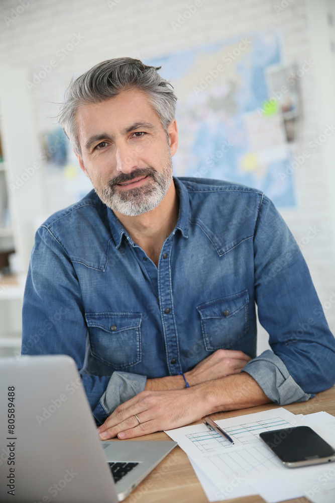 Mature man working on laptop in school office