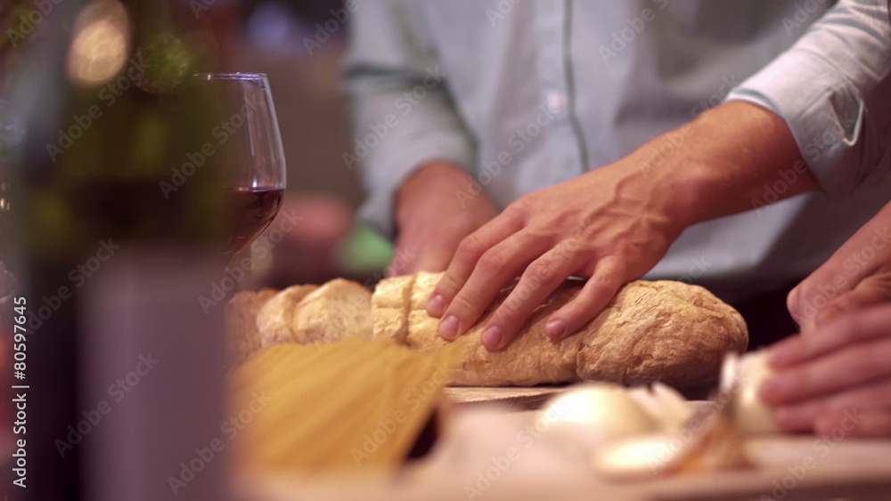 Man cutting bread for dinner with friends Man cutting bread for dinner with friends