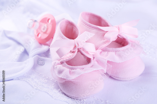Fototapeta Naklejka Na Ścianę i Meble -  Pink baby boots on cloth close-up