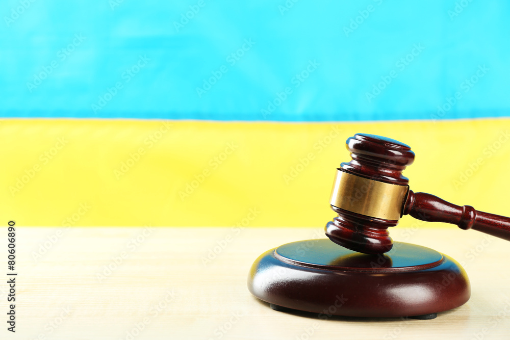 Wooden gavel and flag of Ukraine as background