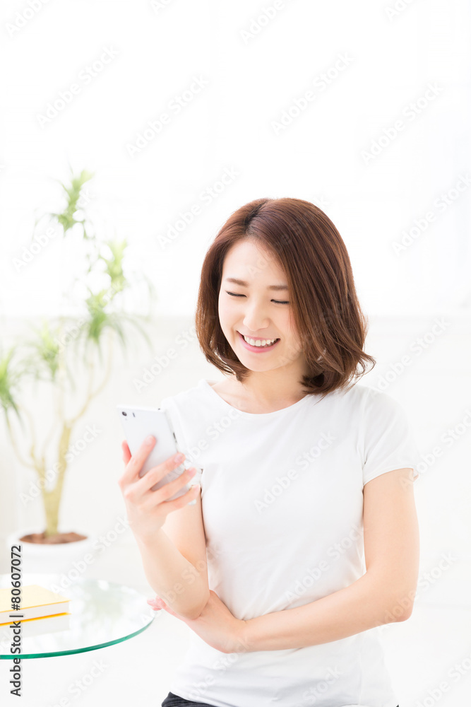 部屋でスマホを見る女性