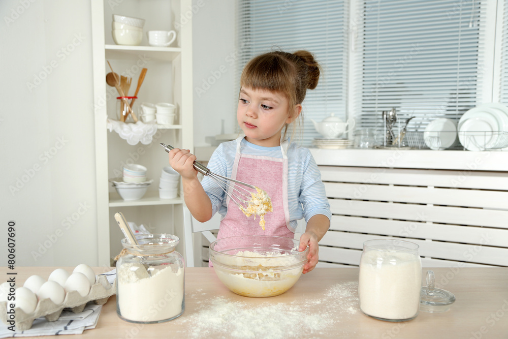 Little girl preparing cookies in kitchen at home