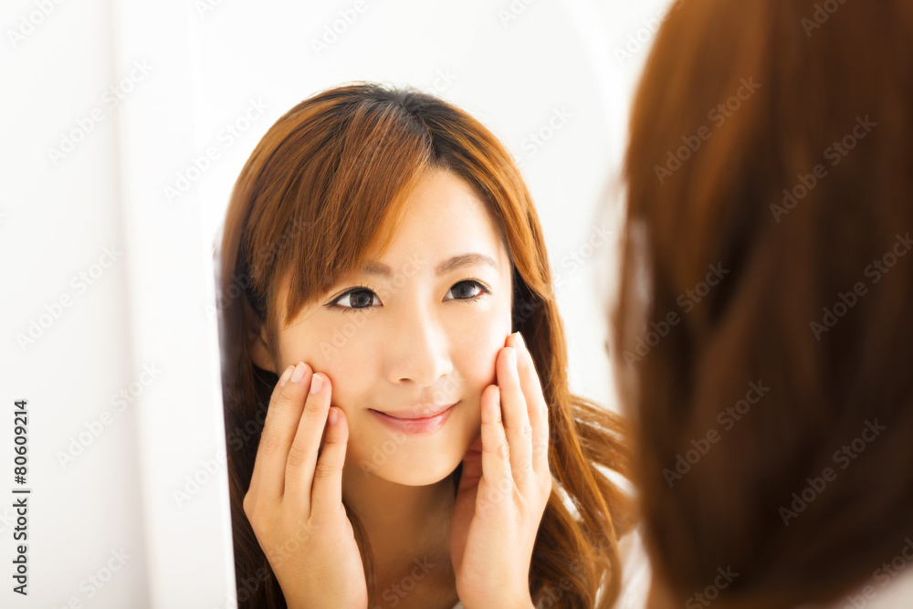 Smiling young woman looking mirror in bedroom Smiling young woman looking mirror in bedroom