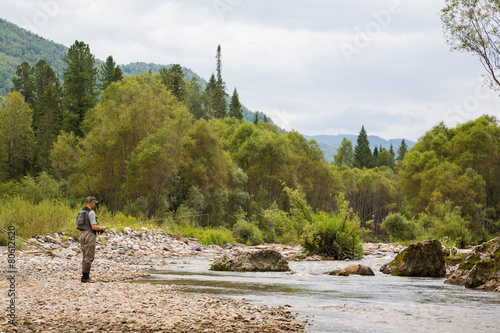 Fly fisherman fishing in mountain river
