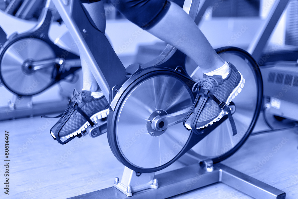 Obraz premium Exercise bike with spinning wheels - woman biking