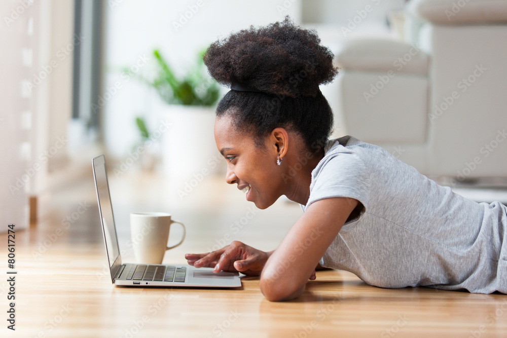 African American woman using a laptop in her living room - Black African American woman using a laptop in her living room - Black
