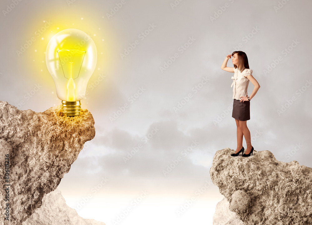 Businesswoman on rock mountain with idea bulb Businesswoman on rock mountain with idea bulb