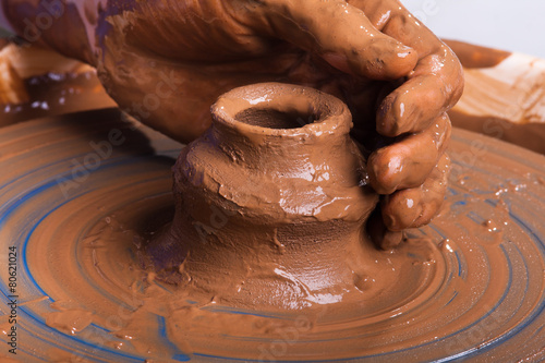 hand of potter with clay jug on pottery wheel