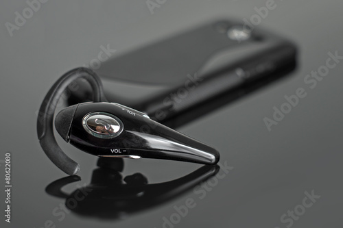 Close-up of handsfree bluetooth device near mobile phone.