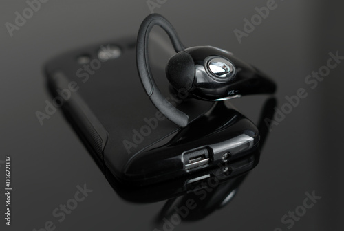 Close-up of handsfree bluetooth device near mobile phone.