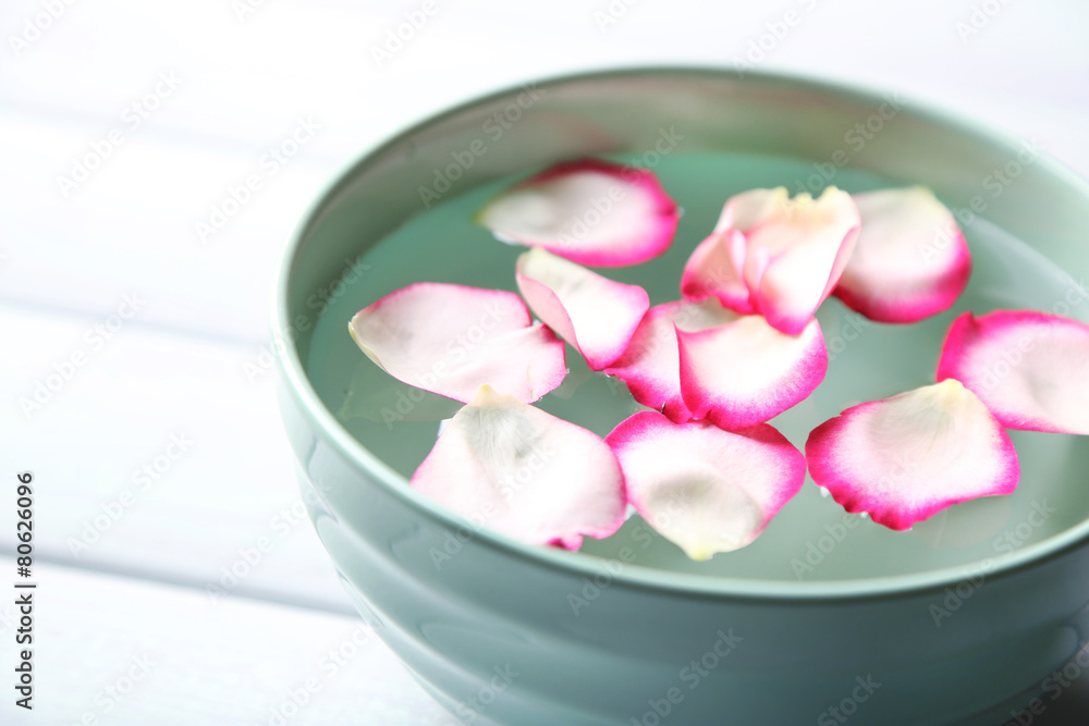 Rose petals in bowl on wooden background