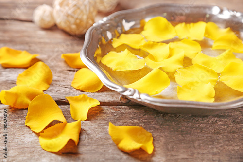 Rose petals in bowl on wooden background