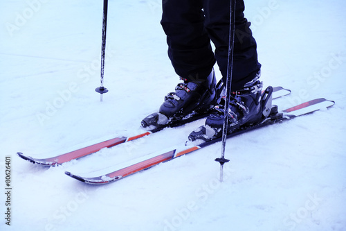 Human legs with skis over white snow background