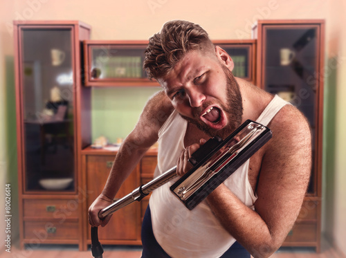 Adult man with beard sings to the vacuum cleaner