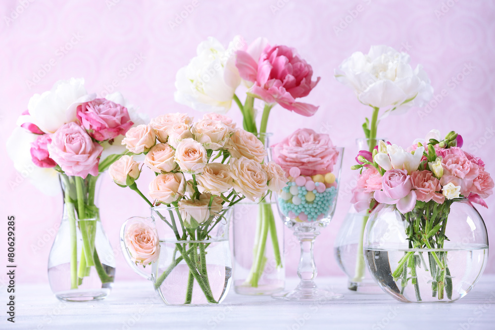 Obraz premium Beautiful spring flowers in glass vases on light pink