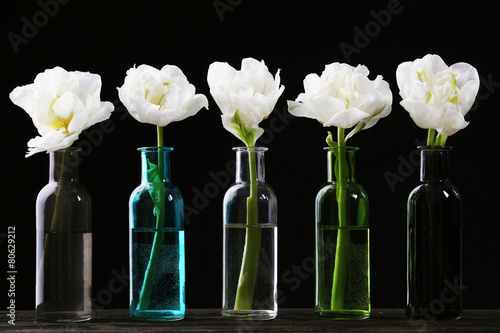Fototapeta Naklejka Na Ścianę i Meble -  Fresh tulips in glass vases on black background