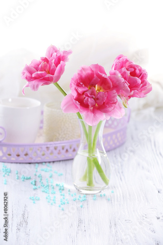 Pink tulips in glass vase on wooden table, closeup