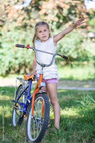 Young girl seven years standing with bicycle in the park