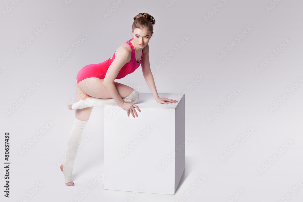 attractive young woman gymnast on a white cube, place for text attractive young woman gymnast on a white cube, place for text