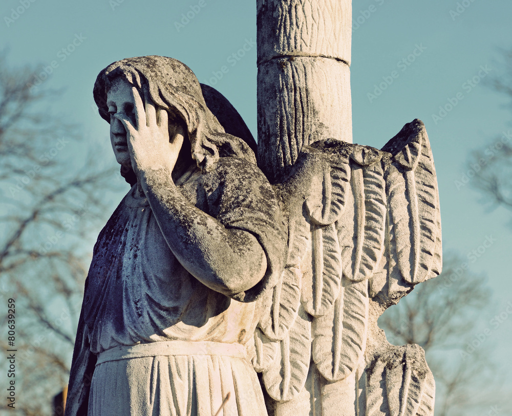 The old stone statue of an angel headstone in the cemetery in vi