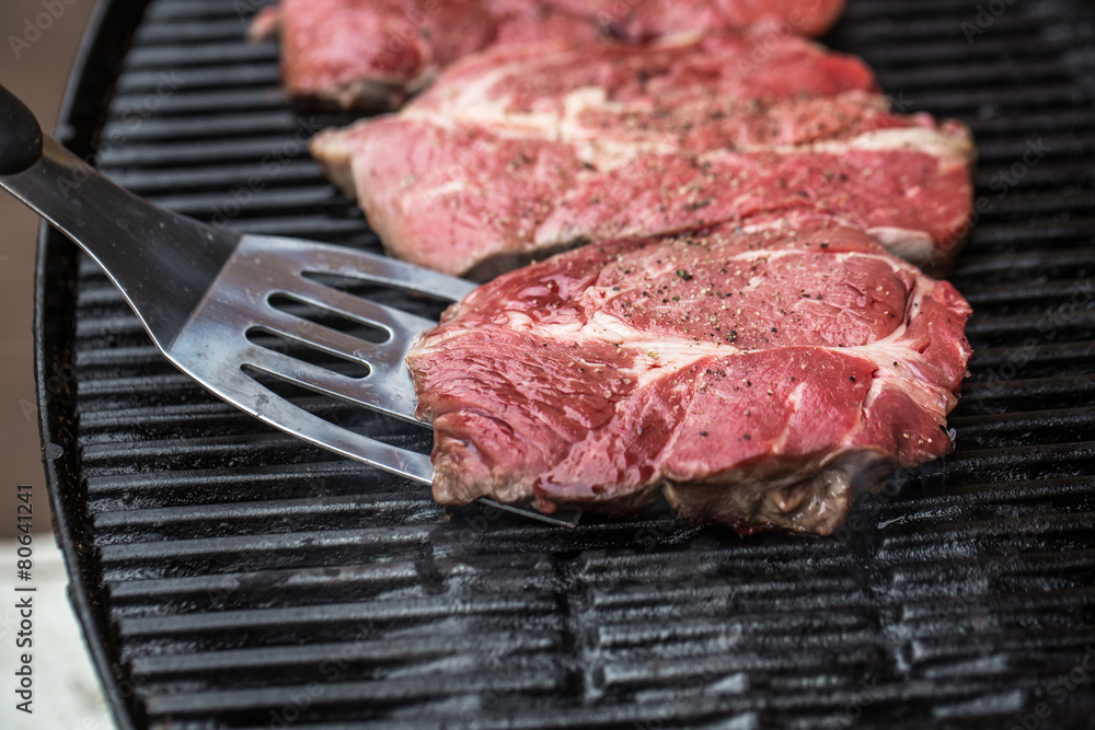 Beef steaks on grill or BBQ with spatula Beef steaks on grill or BBQ with spatula
