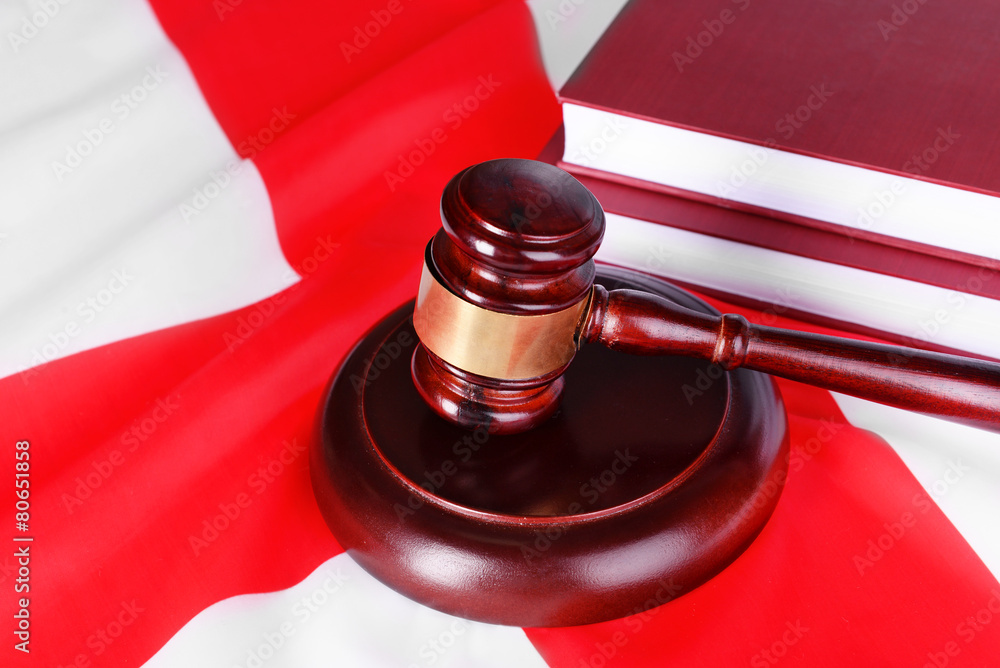 Wooden gavel and books on England flag background Wooden gavel and books on England flag background