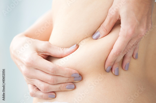 Mujer joven mostrando la grasa localizada en su espalda photo