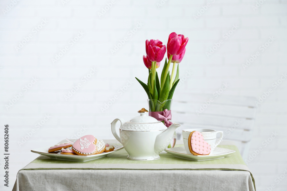Tea set with flowers on table, on light background Tea set with flowers on table, on light background