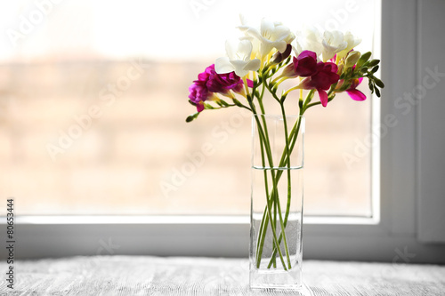 Beautiful spring flowers in glass vase on windowsill background