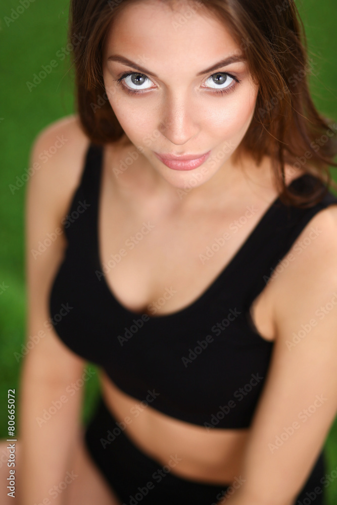 Young fitness girl sitting on green grass Young fitness girl sitting on green grass